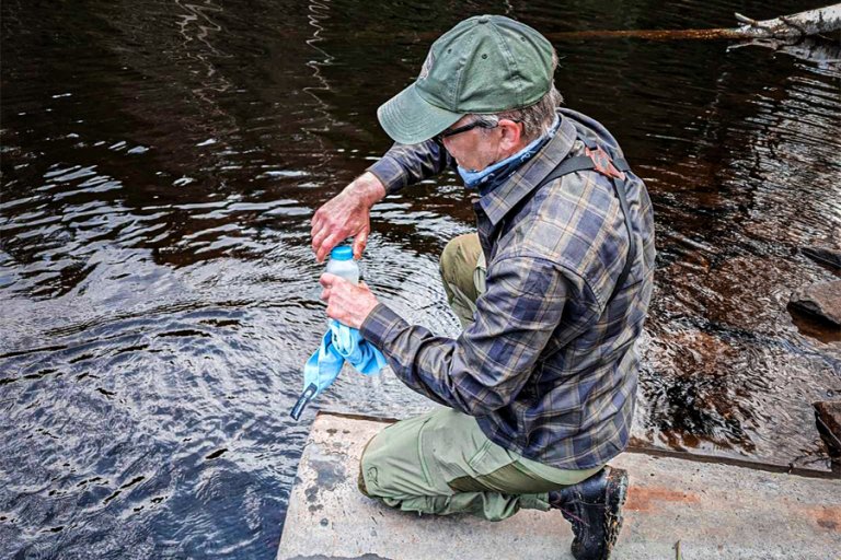 Mann skrur igjen vannflaske sittende på huk