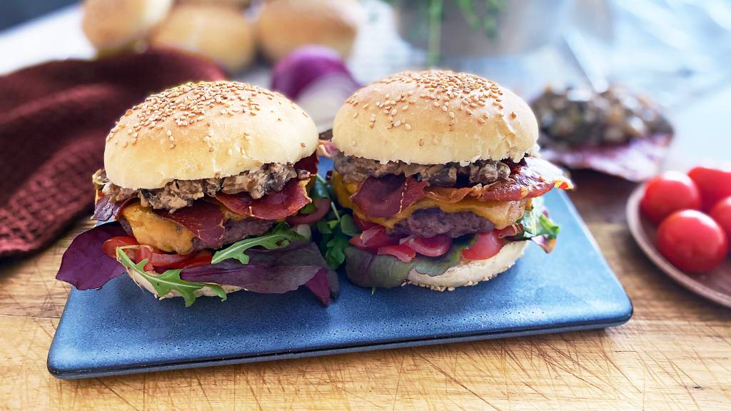 En saftig elgburger egner seg like godt på grillen som i stekepanna. Med en smakfull soppstuing, cherrytomater, spekeskinke og hjemmelagde hamburgerbrød blir dette sommerens vinner.